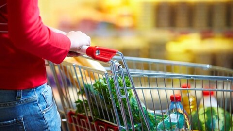 Une femme pousse un panier à l'épicerie