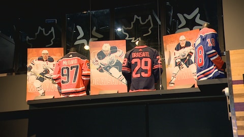 Chandails et photos officiels de trois joueurs des Oilers d'Edmonton placé sur un présentoir. Juin 2024.