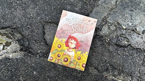 Le livre «Semer des soleils» d'Andrée Poulin déposé sur du béton craquelé.