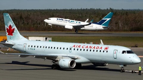 Avion d'Air Canada qui atterrit en premier plan et en arrière plan, un avion de WestJet qui décolle.