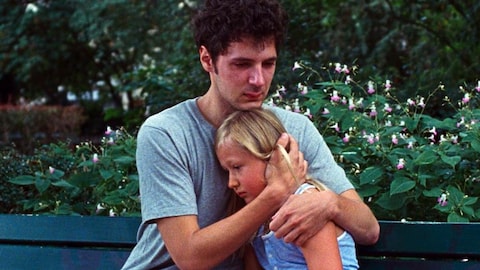 Sur un banc de parc, un jeune homme (Vincent Lacoste) tient une petite fille contre lui.