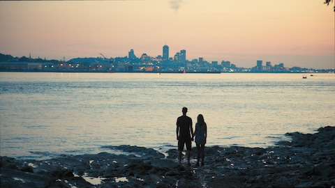 Un homme et une femme se tiennent par la main en regardant le fleuve.