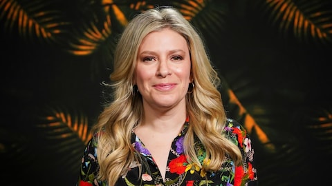 Anne-Marie Withenshaw pose devant une tapisserie aux motifs de forêt tropicale.