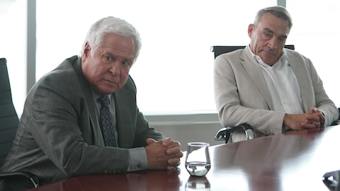 Deux hommes assis à une table de réunion.