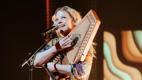 La chanteuse joue d'un instrument sur scène. 