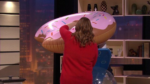 Une personne tient un beignet géant de piscine sur le plateau de Silence on joue.