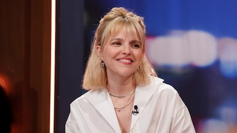 La femme est assise sur le plateau et elle sourit. 