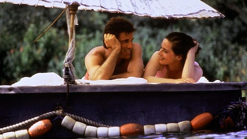 Un homme et une femme, allongés sur le ventre sur un ponton flottant, souriant.