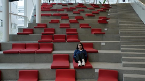 Radio-Canada Une personne est assise seule dans des sièges installés sur des marches de béton.