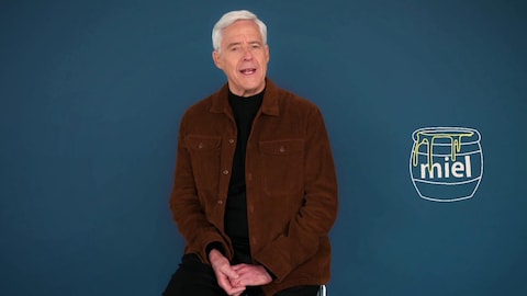 Radio-Canada L'animateur Charles Tisseyre est assis sur un tabouret à côté d'une illustration d'un pot de miel.