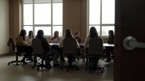 Des femmes discutent autour d'une table dans une salle de réunion.