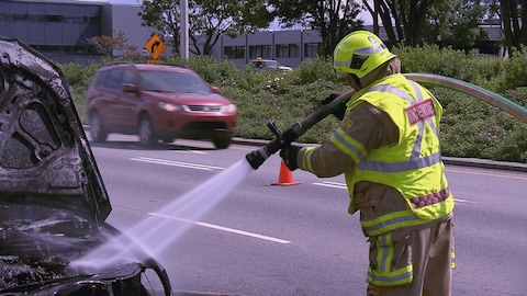 Un pompier qui éteint un feu sur une voiture.