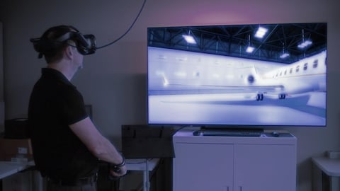 Une personne utilise un casque de réalité virtuelle pour observer la version numérisée d'un aéronef.