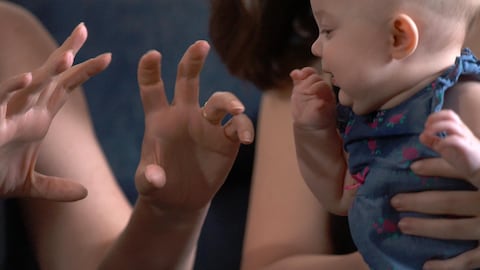 Un bébé qui regarde des mains.