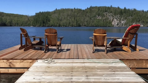 Des chaises Adirondack sur un quai face à un lac.