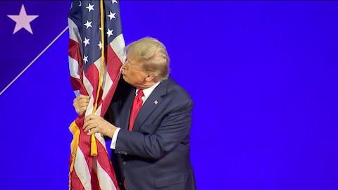 Donald Trump embrasse le drapeau américain alors qu'il est sur scène.