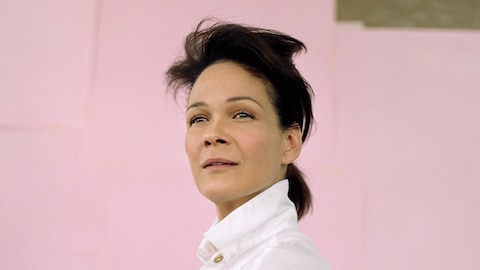 Portrait de la comédienne Sandrine Bisson sur fond rose.
