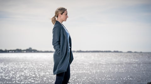 Une femme regarde au loin sur le bord de l'eau.