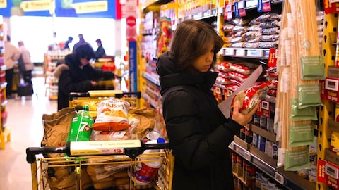 Radio-Canada Une adolescente regarde des produits dans une allée à l'épicerie.