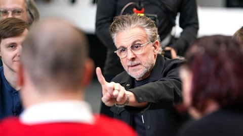 Avanti-Toast / Karine Dufour Patrick Huard lève un doigt en s'adressant à une personne devant lui.