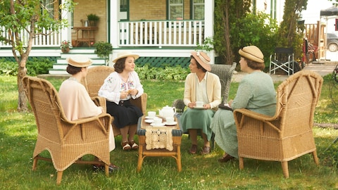 Gabrielle Roy (Romane Denis) et Léa Delorme (Janie Faucher-Roy) prennent le thé avec deux femmes dans la série Le monde de Gabrielle Roy.