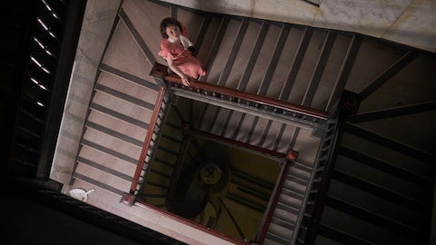 Gabrielle Roy (Romane Denis) dans l'escalier de l'atelier Boutal, dans le 5e épisode de la deuxième saison de la série Le monde de Gabrielle Roy.