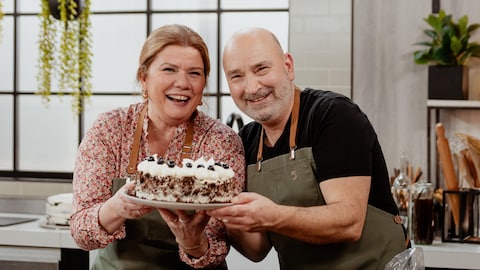 Marina Orsini et Marc Maulà posent avec un gâteau forêt-noire dans la cuisine.