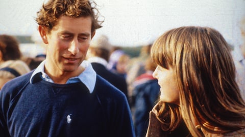 Le prince Charles discute avec une jeune femme dans une foule.