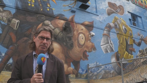 Jean-René Dufort est au micro devant une murale peinte.