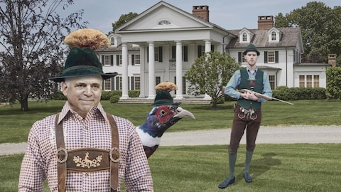 Pierre Fitzgibbon dans un habit folklorique de chasse, portant un chapeau tradiotionnel surmonté de chamois. Il est devant une maison cossue avec un chasseur et un oiseau.