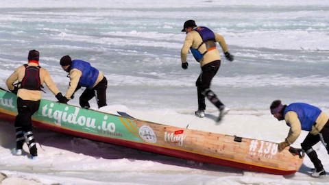 Zone 3 Des canotiers pourssent leur embarcation sur la rive gelée lors d'une compétition de canot à glace.