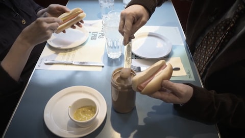 Une table au reataurant ou sont assises deux personnes avec de simples hot dogs.