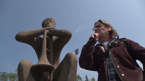 Jean-René Dufort prend la pose à côté d'une statue de trompettiste.