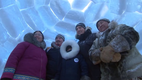 Justin Trudeau pose avec une famille dans un igloo.