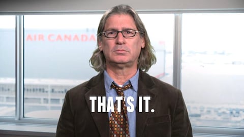 Jean-René Dufort regarde la caméra. Le logo d'Air Canada est en arrière plan. 