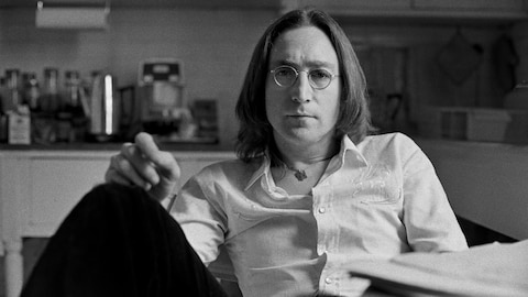 John Lennon assis confortablement à la table dans une cuisine.