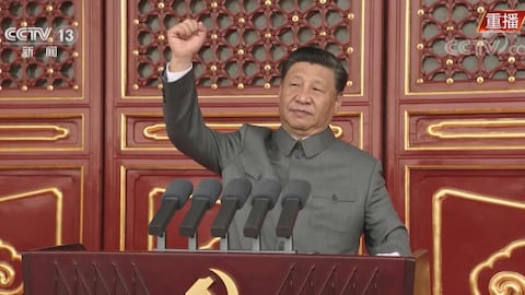 Un leader chinois lève le poing sur une tribune.