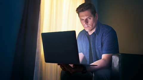 Portrait de Patrick Lagacé qui regarde un ordinateur portable.