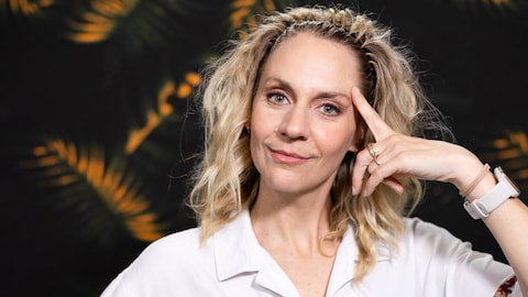 Léane Labrèche-Dor pose devant une tapisserie à motifs tropicaux.