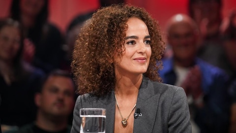 A Média Une femme qui sourit. Un verre d'eau est posé devant elle.