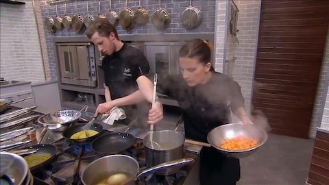 Marc-Antoine brasse une sauce dans une poêle et Ashley sort des aliments d'un chaudron.