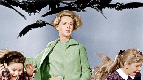 Une femme (Tippi Hedren) poursuivie par des oiseaux court avec deux enfants.