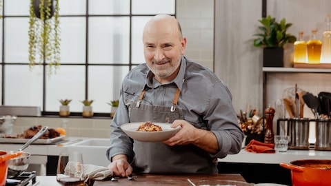 Marc Maulà pose dans la cuisine avec une assiette de ragoût de veau.