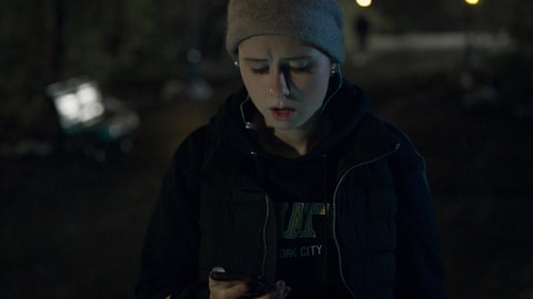 Le personnage de Cerebrum est dans un sentier la nuit et regarde son téléphone d'un air apeuré. 