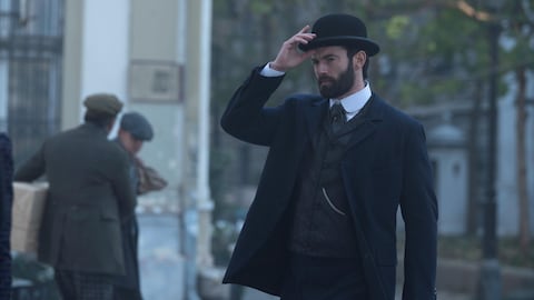 Le Duc, joué par l'acteur Stuart Martin, tient son chapeau dans la rue.