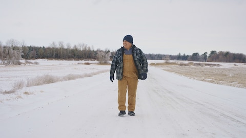 Un homme qui marche sur une route enneigée.