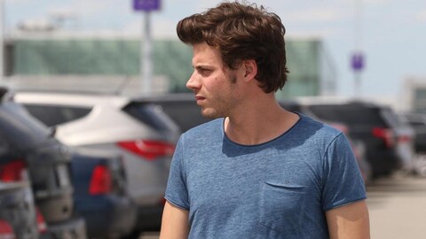 Un homme (François Arnaud), dans un stationnement, regarde vers sa droite.