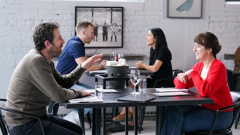 Un homme et une femme sont assis à une table et ils discutent.