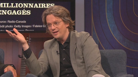 Pierre-Yves McSween regarde la caméra. Le bout d'une des branches de ses lunettes est posé sur sa bouche.