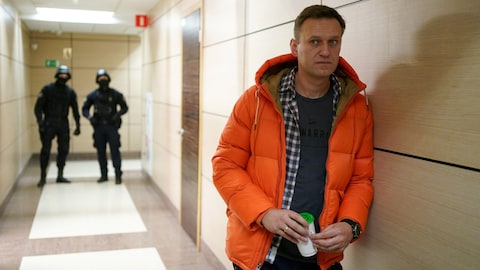 L'opposant russe Alexeï Navalny se tient près des agents des forces de l'ordre dans un couloir d'un centre d'affaires.